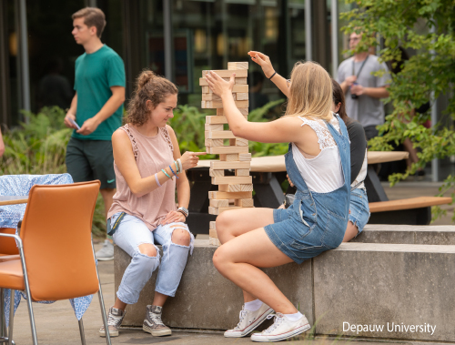 A photo of DePauw University students playing Jenga outside on a patio.